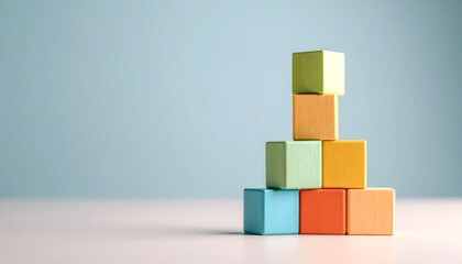 Stack of colorful wooden blocks forming a small pyramid shape on a soft blue background, symbolizing growth and balance.