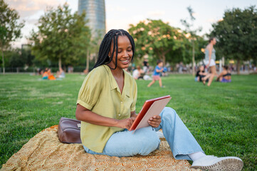 Happy student using tablet in a park during summer