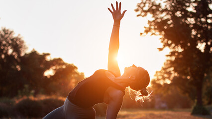 Woman practicing yoga and stretching in the park on a hot sunny summertime day.