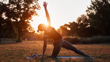 Woman practicing yoga and stretching in the park on a hot sunny summertime day.