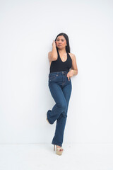 A stylish young Asian woman in a full body shot standing elegantly, fixing her hair with one hand and casually putting the other hand in her pocket. Isolated on a white background.