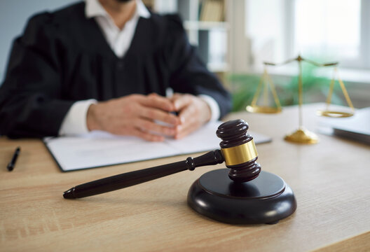 Close-up of gavel, hammer or mallet with judge in courtroom during lawsuit session, focusing on law and sentence in a professional setting with a sense of judgment and legal authority and enforcement.