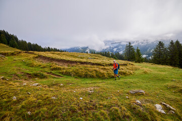 Fototapeta premium a strong old man climbing a mountain on a cloudy day