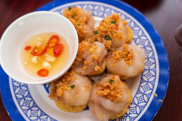 Six servings of  Ram It Cake  from Hue are presented on a blue and white patterned plate, featuring steamed rice cakes on fried crispy bases.