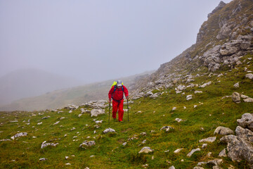 Obraz premium a strong old man climbing a mountain on a cloudy day