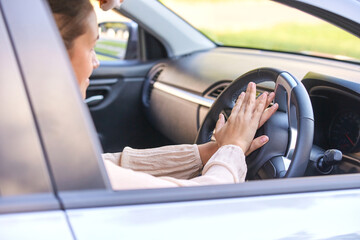 Female driver pressing car horn inside vehicle focused on attention and awareness.