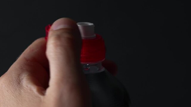 A man opens the cap on a sports bottle with a dispenser.
Dispenser on a plastic bottle.
Red dispenser on a sports water bottle.
Push-pull cap