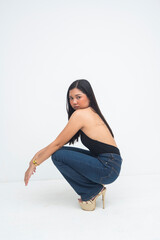 An expressive young Asian woman captured from the side, crouching with a fierce editorial pose and striking, powerful eyes. Isolated on a white background.