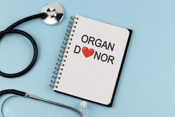 Stethoscope and notebook with text organ donor on blue background