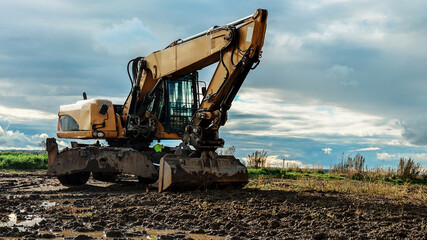 Yellow excavator parked on muddy construction site