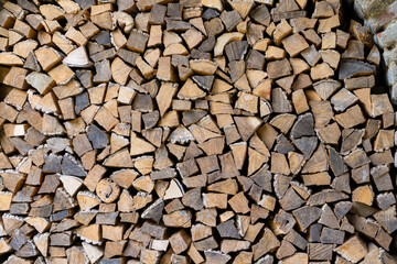 Close up view of stacked firewood neatly cut to the same size. Yellow, light brown and brown colors