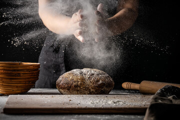Baker with fresh sourdough bread and flour dust