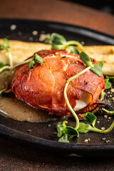 Close-up of prosciutto wrapped meat with microgreens