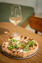 Italian pizza with white wine on wooden table.