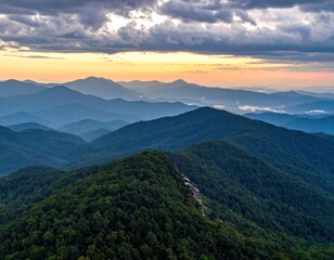 Fototapeta premium Aerial view of layered green mountains under a moody, colorful sunset sky. Atmospheric perspective creates depth and serene beauty