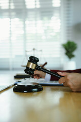 A lawyer carefully reviews and points to a contract document with a pen, beside a laptop, gavel, and justice scales.