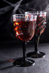 Halloween spooky red cocktail in skeleton hand glass on black background