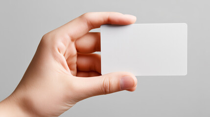 Close-up of hand holding blank white business card against a neutral background. Ideal for showcasing personalized text, graphic designs, or branding purposes in professional  creative presentations.