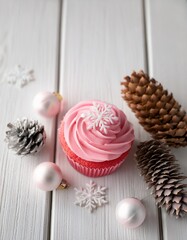 Fototapeta premium Christmas background. Top view of pink glazed cupcake with sugar snowflakes decoration on white wooden background. Generated image