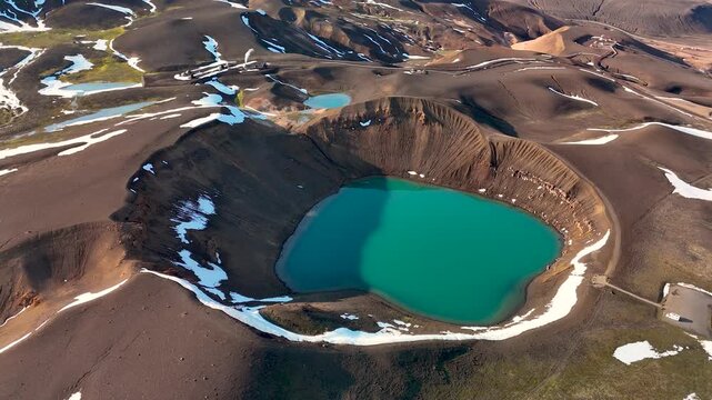 Nestled in the highlands of Iceland, Krafla crater features a vibrant turquoise lake surrounded by rugged terrain and snow-capped peaks.