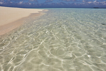 Pristine shallow waters lap against the white coral sand of a tropical beach; Havodda Island, Gaafu Dhaalu atoll, Maldives