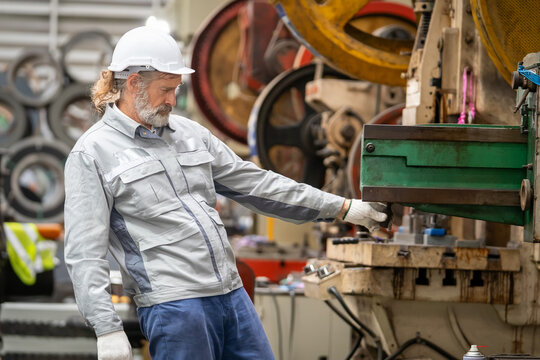 Industrial worker operating machinery manufacturing facility action shot workshop environment focused viewpoint safety practices