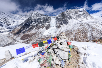 Stone Cairn Adorned with Prayer Flags on the Wind-Swept Summit of Kyanjin Ri with Langtang Lirung and Langtang Glacier Behind