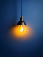 Warm-lit pendant lamp against blue wall promoting creative interior design and visual storytelling
