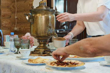 Traditional tea drinking with a samovar, cups, and homemade pancakes on the table.
