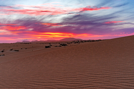 Fiery sky at sunset over sand dunes shaped by wind, Corralejo Natural Park, Fuerteventura, Canary Islands, Spain