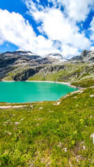 Austria, 08-2025 : wide shot of Weißsee lake, mountains and glaciers in background, grass in foreground.