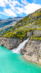 Austria, 08-2025 : waterfall in the weißsee reservoir lake. Mountain and blue sky in background.