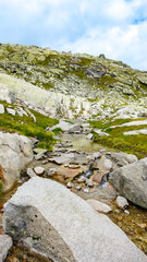 Austria, 08-2025 : wide shot of mountains rocks and a mountain river, near the weißsee lake.