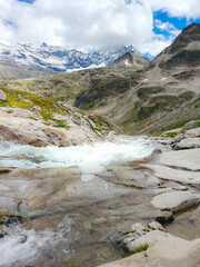 Austria, 08-2025 : wide shot of mountains rocks and a mountain river, near the weißsee lake. Moutains and blue sky in background.
