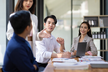 Group businesspeople happy while collaborating on a new project in an office. Businessman leading a discussion during a meeting with colleagues. Businesswoman interacting with a colleague.