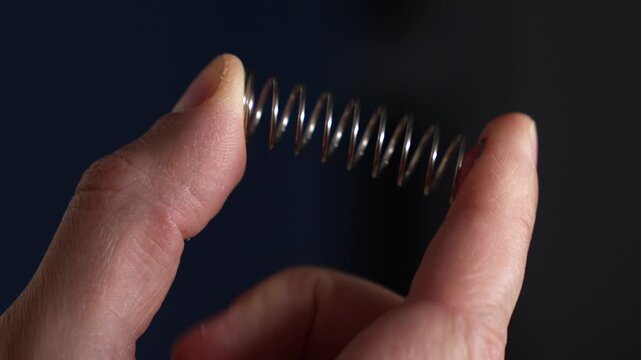 A man squeezes a tight, strong spring with his thumb.
A close-up of a metal spring in a man's hands.
Spring, metal, part, bending