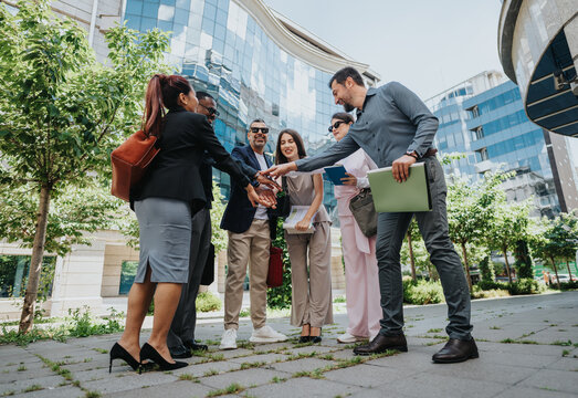 A team of diverse colleagues engaging in a collaborative activity outdoors near office buildings, showcasing teamwork, positivity, and a professional environment.