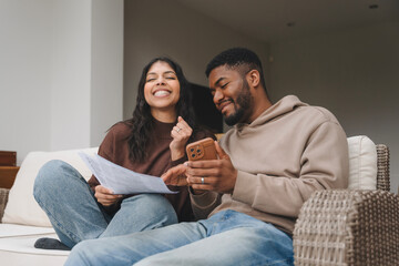 Couple enjoying a relaxed moment together while reviewing documents and using a smartphone in a cozy indoor setting