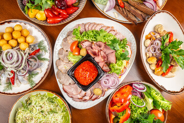 Assorted appetizers with smoked meats, salads, vegetables, and sauces on a festive table