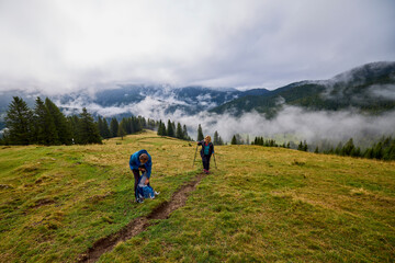 Obraz premium A middle-aged couple hiking up a mountain on a cloudy and foggy day.