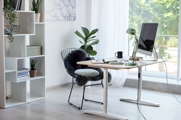 Home workspace. Modern computer, houseplant and stationery on wooden desk indoors