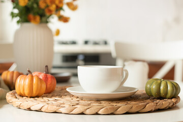 Warming autumn tea in white cup, orange flowers in vase at modern kitchen. Cozy home interior with coffee break. Close up.