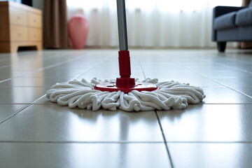 String mop cleaning light tiled floor in modern home. Close-up of mopping process, representing domestic chores, professional cleaning service, and maintaining household hygiene and cleanliness