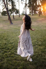 Obraz premium Carefree asian girl in dress laughing and dancing in park, enjoying summer sunset, raising hands up and breathing fresh air.