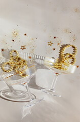 Champagne glasses and Christmas, festive , party decoration gold balls, confetti, stars,  serpentine top view on beige background.New Year, holiday, birthday, wedding mockup ,template with copy space.