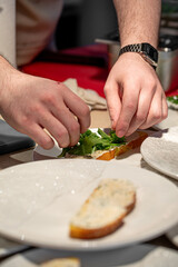 Male chef adds greens on bruschetta in restaurant kitchen
