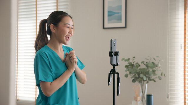 Young adult woman Gen Z asia people anti aging expert modern nurse live talk viral video selfie camera on mobile phone app mental health care. Online sharing digital virtual asian vlogger filming.