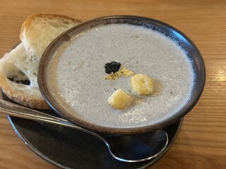 A rich and creamy Truffle Mushroom Soup served in a rustic bowl, garnished with black truffle bits and croutons, accompanied by toasted bread slices on a wooden table.