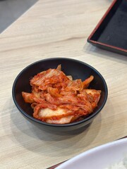 Traditional Fermented Korean Food: Two Vertical Images of Vibrant, Spicy Napa Cabbage Kimchi (Baechu Kimchi) Side Dish, Served in a Dark Black Bowl on Wood.