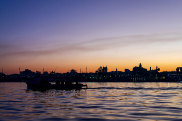 Fototapeta premium Silhouette of a motorboat egyptian ferry on the Nile river, Luxor East bank at sunrise, Egypt